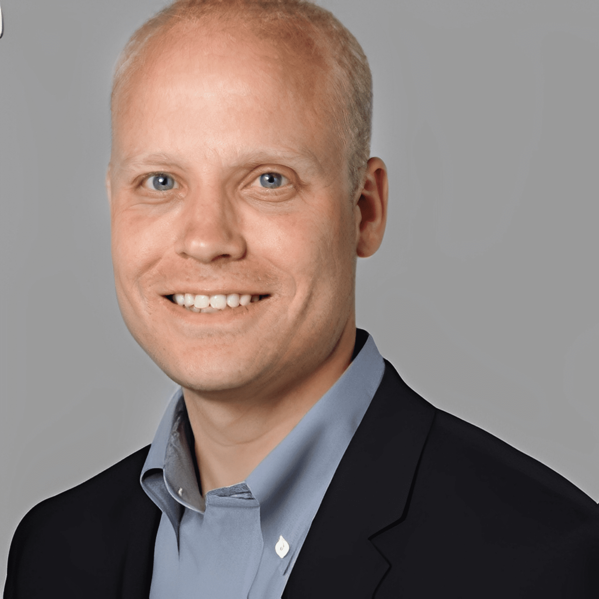 Professional headshot of a smiling man in business attire.