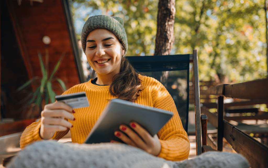Woman enjoying coffee while using a tablet outdoors.