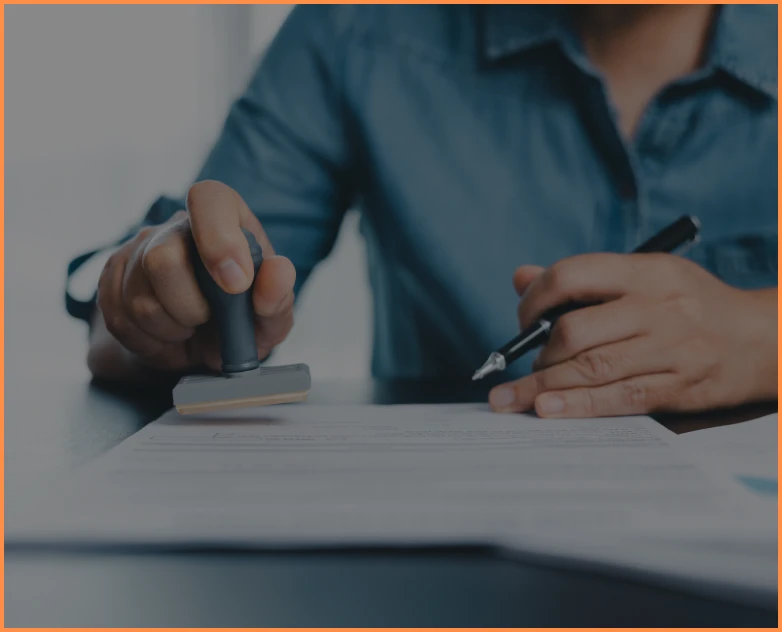 Hand holding stamp over paperwork